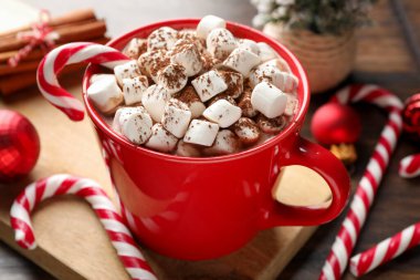 Marşmelovlu lezzetli kakao, baston şekerler, tarçın ve Noel süsü ahşap masada, yakın plan.