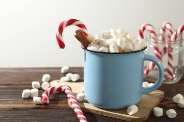 Noel atmosferi. Marşmelovlu lezzetli kakao, şeker kamışı ve ahşap masada tarçın, yakın plan. Metin için boşluk