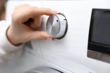 Beyaz çamaşır makinesini çalıştıran kadın, yakın plan.