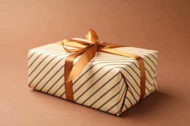 Kahverengi arka planda güzel paketlenmiş hediye, yakın plan.