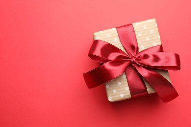 Kırmızı arka planda fiyonklu güzel bir hediye, üst manzara. Metin için boşluk