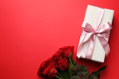 Güzel bir hediye ve kırmızı arka planda güller, metin için yeri olan düz bir yer. Sevgililer Günü