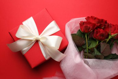Güzel bir hediye ve kırmızı arka planda güller, düz yatış. Sevgililer Günü