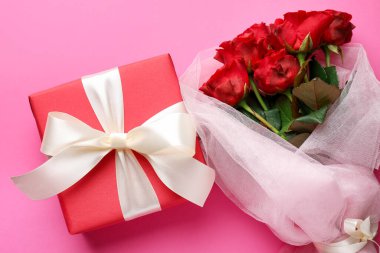 Sevgililer Günü. Güzel bir hediye ve pembe arka planda güller, düz yatış.