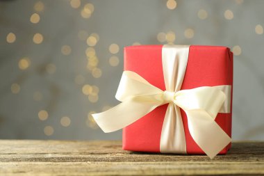 Ahşap masada gri arka planda Bokeh efektli güzel bir hediye, yakın plan. Metin için boşluk