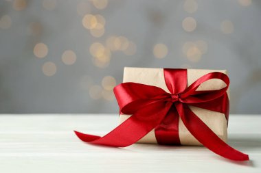 Beyaz ahşap masada gri arka planda Bokeh efektli güzel bir hediye, yakın plan. Metin için boşluk
