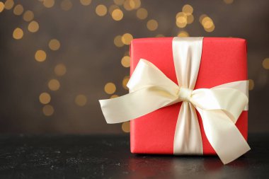 Gri arkaplanla siyah masada güzel bir hediye. Bokeh efektli, yakın plan. Metin için boşluk