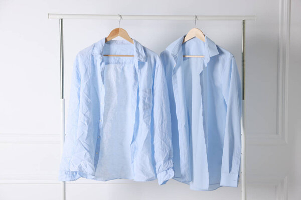 Creased and ironed shirts on hangers against white wall