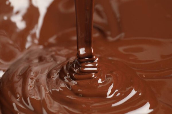 Tasty melted chocolate flowing down, closeup view