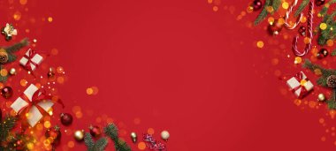 Noel baloları, hediye kutuları, köknar dalları ve kırmızı arka planda şeker kamışları, üst manzara. Metin için yeri olan tebrik kartı ya da poster