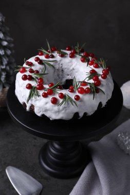 Yaban mersinli, biberiyeli, sunuculu ve gri masadaki şenlikli Noel pastası. Yakın plan.