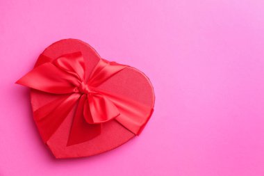 Sevgililer Günün kutlu olsun. Pembe arka planda kalp şeklinde hediye kutusu, üst manzara. Metin için boşluk