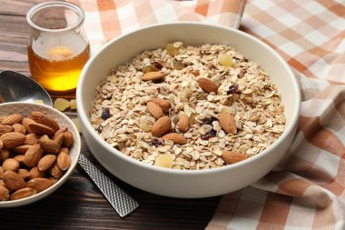 Tahıl yapıyorum. Yulaf gevreği, kurutulmuş meyve, badem fıstığı ve bal ahşap masada, yakın plan.