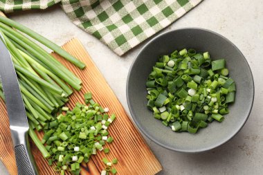 Açık gri masada yeşil soğan ve bıçak kes, düz yat.