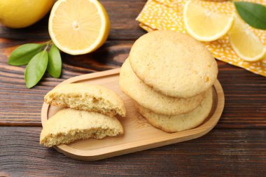 Lezzetli limonlu kurabiyeler ve ahşap masada meyve dilimleri, yakın plan.
