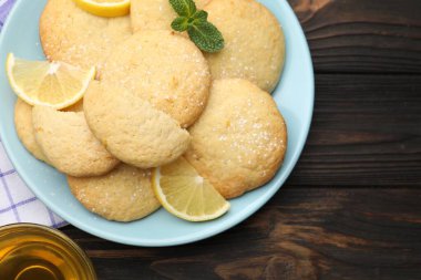 Lezzetli limonlu kurabiyeler ve siyah ahşap masadaki meyve dilimleri.