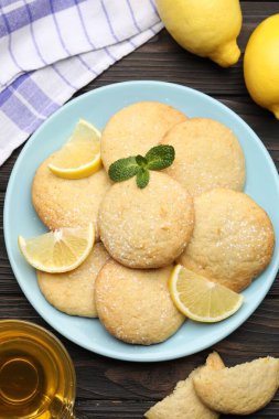 Lezzetli limonlu kurabiyeler ve siyah ahşap masa üzerindeki meyve dilimleri.