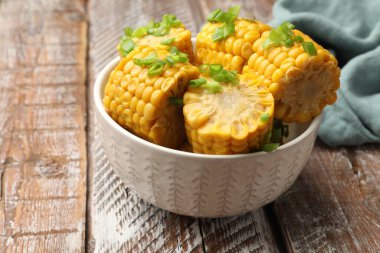 Ahşap masada yeşil soğanlı haşlanmış mısır koçanları, yakın plan.