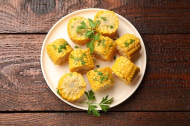 Ahşap masada maydanozlu haşlanmış mısır koçanı parçaları.