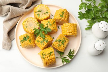 Beyaz mermer masada maydanozlu haşlanmış mısır koçanı parçaları.