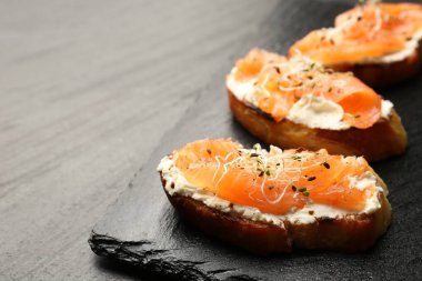 Somonlu lezzetli bruschettalar, krem peynir ve siyah masada mikroyeşiller, yakın plan. Metin için boşluk