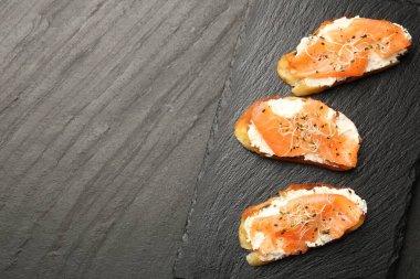 Somonlu lezzetli bruschettalar, krem peynir ve siyah masada mikroyeşiller. Metin için boşluk