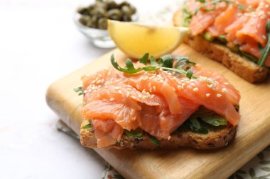 Somon, roka, avokado ve susam tohumlu leziz bruschetalar beyaz mermer masada, yakın plan.