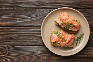 Somon, avokado, roka ve ahşap masada susam tohumlu lezzetli bruschetta. Metin için boşluk
