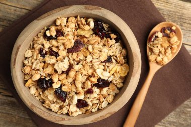 Lezzetli tahıl gevreği, kuru meyveler kasede ve kaşık tahta masada, düz uzanmış.