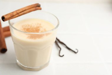 Bardakta lezzetli protein karışımı, beyaz masada tarçın ve vanilya kapsülleri, yakın plan. Metin için boşluk