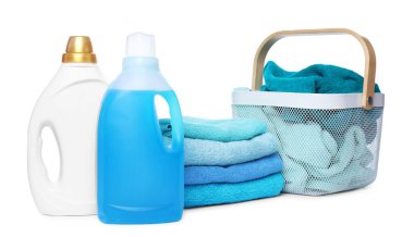 Çamaşır sepeti, yumuşak havlular ve beyaza izole edilmiş deterjan şişeleri.