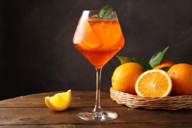 Bir bardak ferahlatıcı spritzer kokteyli. Nane ve portakallar ahşap masada.