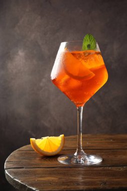 Bir bardak ferahlatıcı spritzer kokteyli. Nane ve portakal dilimli ahşap masa.