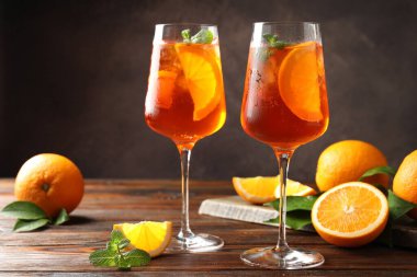 Serinletici spritzer kokteyli ve portakallar ahşap masada.