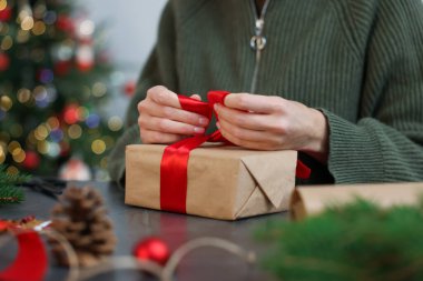 Gri masada Noel hediyesini paketleyen kadın, yakın plan.