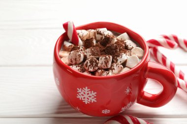 Noel atmosferi. Marşmelovlu ve beyaz ahşap masada şeker kamışlı lezzetli kakao, yakın plan. Metin için boşluk