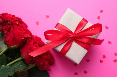 Sevgililer Günün kutlu olsun. Hediye kutusu, konfeti ve pembe arka planda bir buket kırmızı gül.