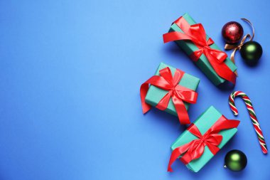 Paketlenmiş Noel hediyeleri ve mavi arka planda dekorasyon, düz yatış. Metin için boşluk