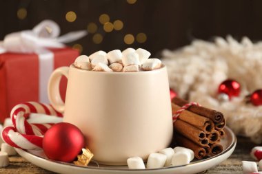 Marşmelovlu lezzetli kakao, baston şekerler, tarçın ve Noel süsü ahşap masada, yakın plan.