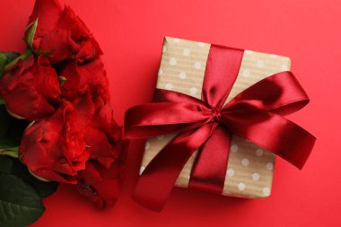 Güzel bir hediye ve kırmızı arka planda güller, düz yatış. Sevgililer Günü