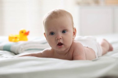 Bebek bezli şirin bir bebek, havlu ve yatağın içinde lastik ördekler.