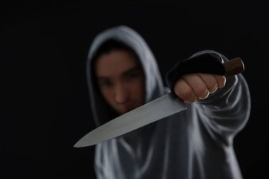 Siyah arka planda bıçaklı, seçici odaklı bir suçlu. Metin için boşluk