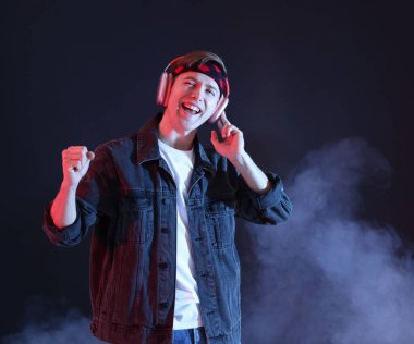 Kulaklıkla müzik dinleyen ve dumanla arka planda dans eden bir adam.