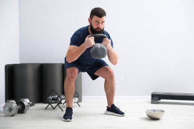 Spor salonunda kettlebell ile egzersiz yapan güçlü bir adam.
