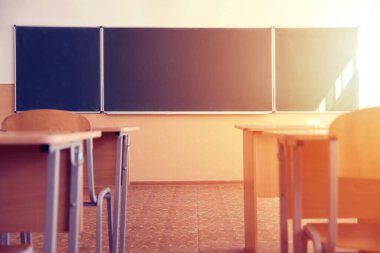 Güneşli bir günde kurul, sandalye ve masalarla dolu bir sınıf seçici bir odak noktası.