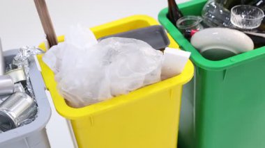 Çöp tenekeleri beyaz arka planda, kamera sağa hareket ediyor. Atık sıralama