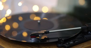 Masada plak plağı olan döner masa, yakın plan. Noel ışıkları disk yüzeyine yansıyor