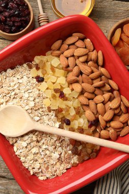 Tahıl yapıyorum. Yulaf gevreği, kurutulmuş meyve, badem fıstığı ve bal ahşap masada, düz uzanmış.