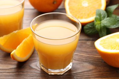 Taze portakal suyu, nane ve ahşap masada meyveler, yakın plan.