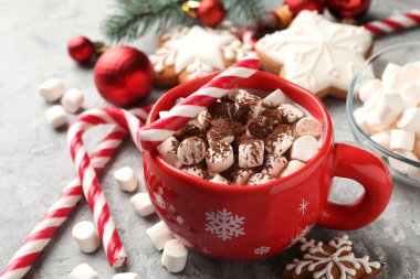 Marşmelovlu lezzetli kakao, baston şekerler, zencefilli kurabiyeler ve gri masada Noel dekoru, yakın plan.